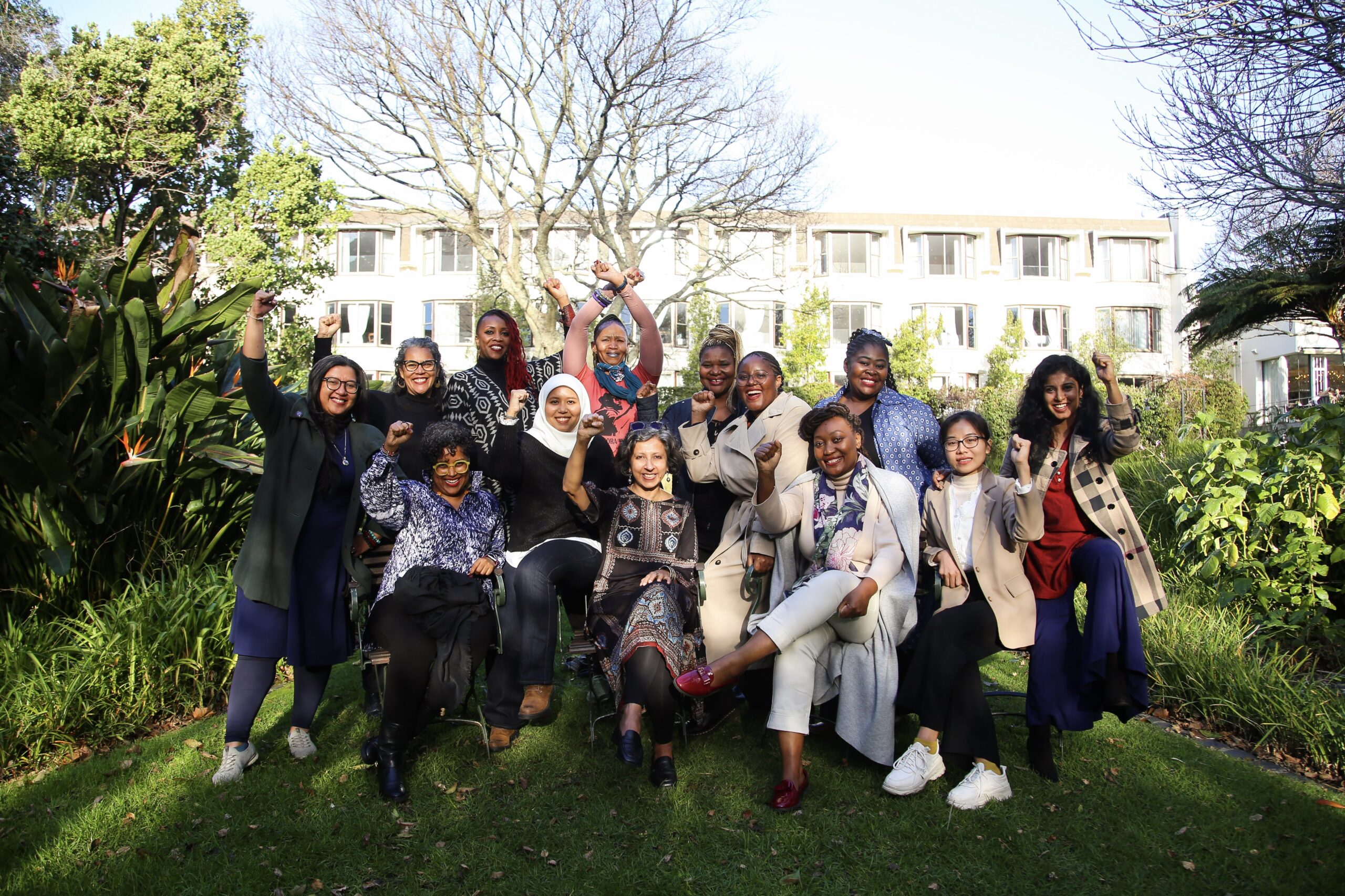 Members of the Gender and Trade Coalition gathered outdoors with fists high at Third Strategy Meeting.