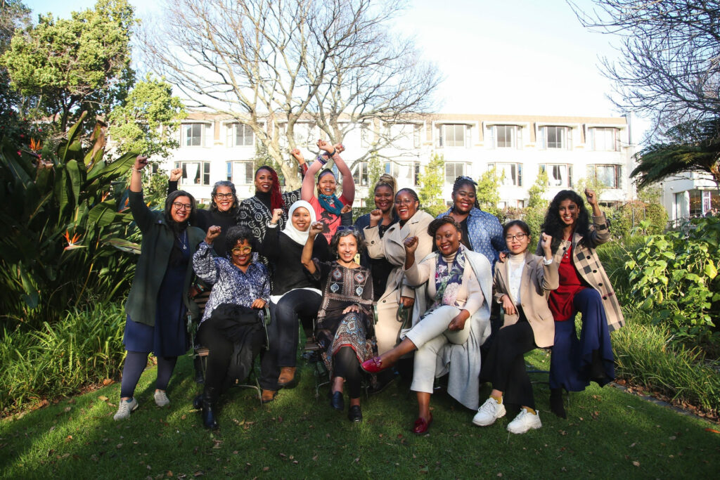 Members of the Gender and Trade Coalition gathered outdoors with fists high at Third Strategy Meeting.