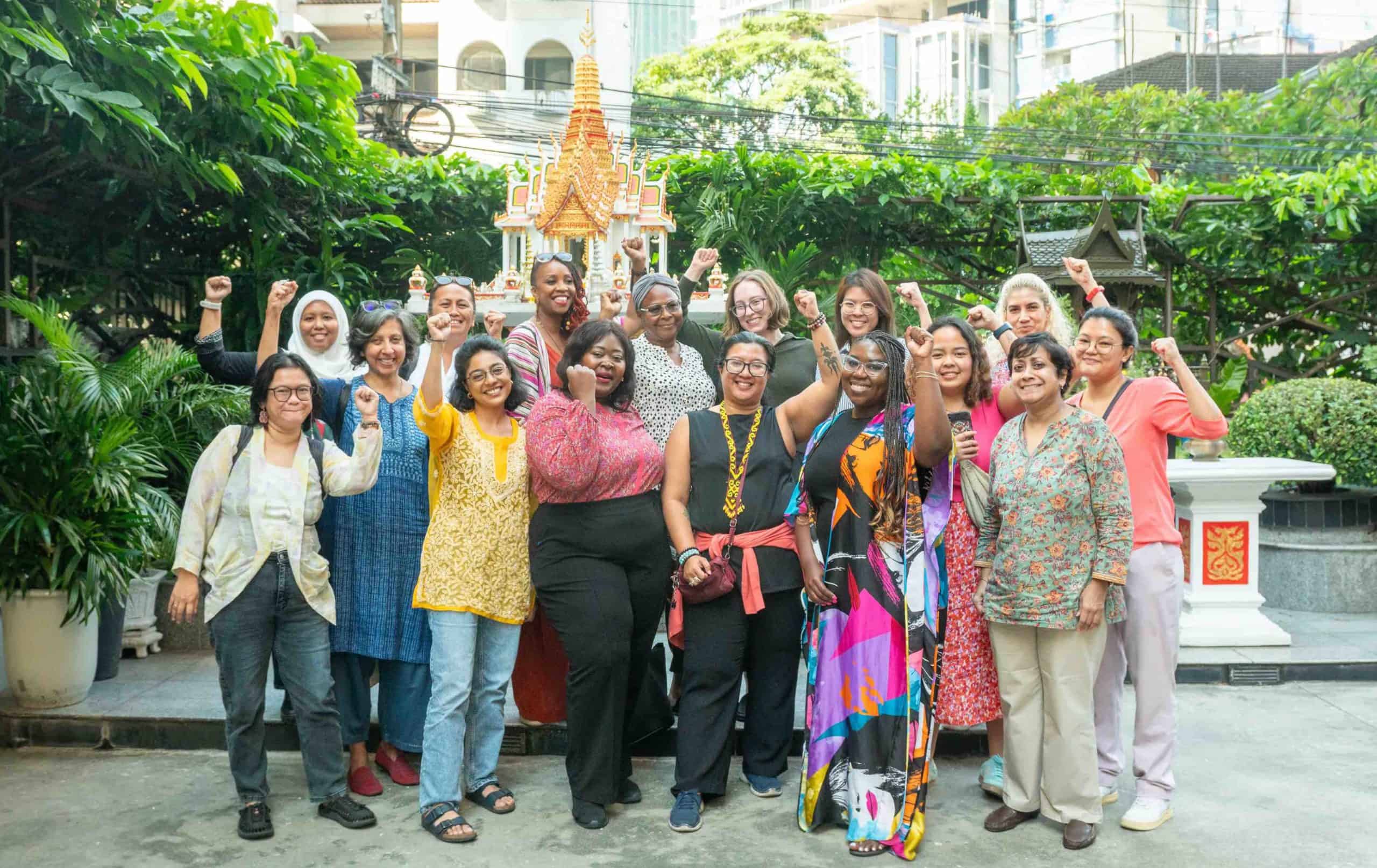 Members of the Gender and Trade Coalition gathered outdoors with fists high at our Fourth Strategy Meeting.